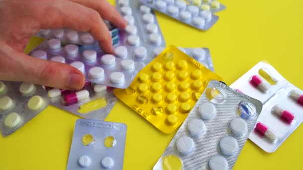 Sarı arka planda tabletleri olan tıbbi su toplayıcılarını kapatın. Çeşitli tabletlerle dolu paketler. Çeşitli hastalık tehdidi kavramı. — Stok video