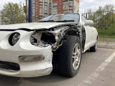 Voronezh, Rusya 29 Nisan 2020: bir kazadan sonra kaputu ve tamponu göçmüş beyaz araba. Asfaltlı park yerine park etmiş buruşuk metal şapkalı eski bir araba.