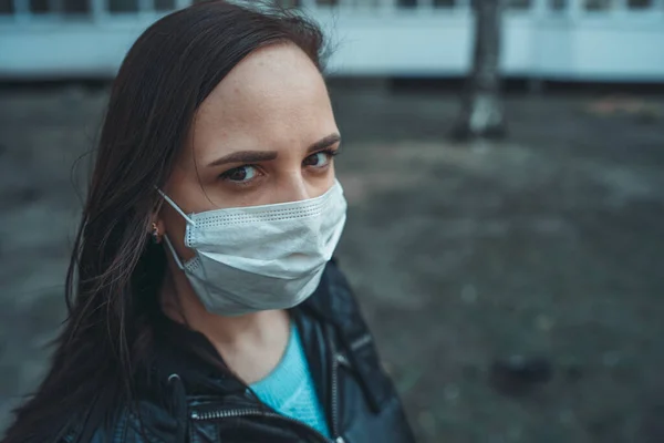 Portret młodej kobiety w masce medycznej na twarzy stojącej na ulicy. Dorosła samica przykryła twarz maską, by chronić się przed chorobami.. — Zdjęcie stockowe