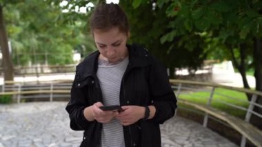 Ofisin yanında cep telefonu kullanan bir kadın, telefonuna göz atan güzel bir kadın ve mobil bir uygulamayla online alışveriş yapan bir kadın. Çevrimiçi iletişim.