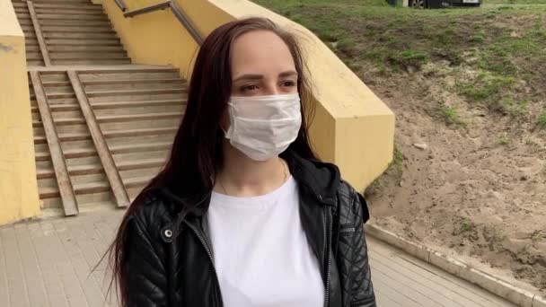 Junge Frau in medizinischer Maske auf der Straße. Erwachsene Frauen schützen sich vor Krankheiten. Konzept der Bedrohung durch Coronavirus-Epidemie. — Stockvideo