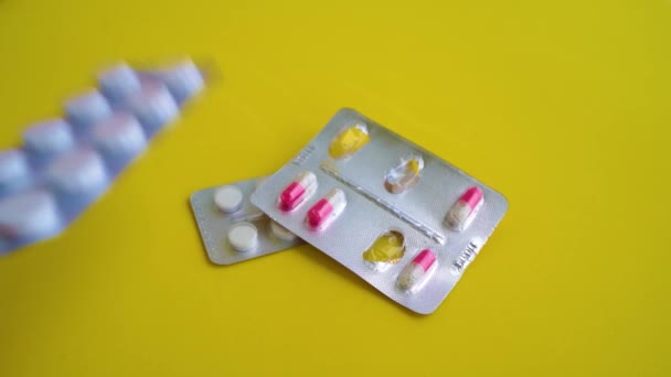 Close up of medical blister packs with tablets on yellow background. Packs with various tablets. Concept of threat of various diseases. — Stock Video