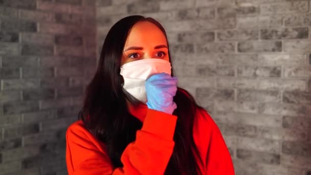 의료용 마스크와 장갑을 끼고 주먹으로 기침하는 젊은 여자 가집에 고립되어 있다. 성인 여성은 질병으로부터 자신을 보호 합니다. 코로나 바이러스 의유 행병 감염의 위협에 대한 개념. — 비디오