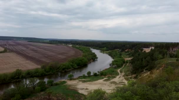 Cicha rzeka na wsi. Z góry, niesamowita rzeka ze spokojną wodą położoną obok wiosennego lasu w przyrodzie. Wąska, kręta rzeka przepływająca przez gaj drzew. — Wideo stockowe