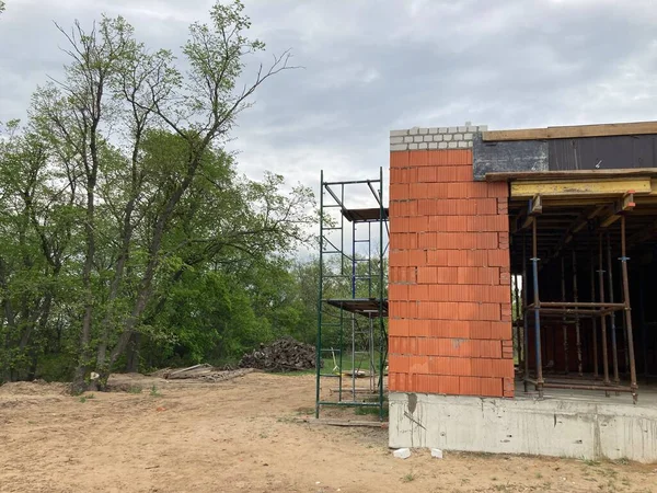 Fechar a casa inacabada na área residencial. Arquitetura moderna de casa de tijolo de construção para estadia confortável de pessoas . — Fotografia de Stock