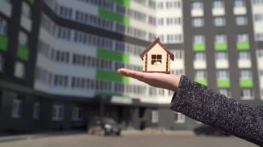 Kadınlardaki küçük ahşap evin arka planında inşa edilmiş bir ev var. Yeni daire satın alma kavramı.