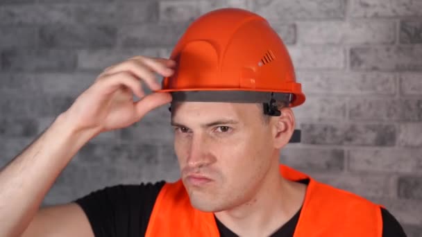 Hombre en uniforme de trabajo girando naranja protector hardhat — Vídeos de Stock