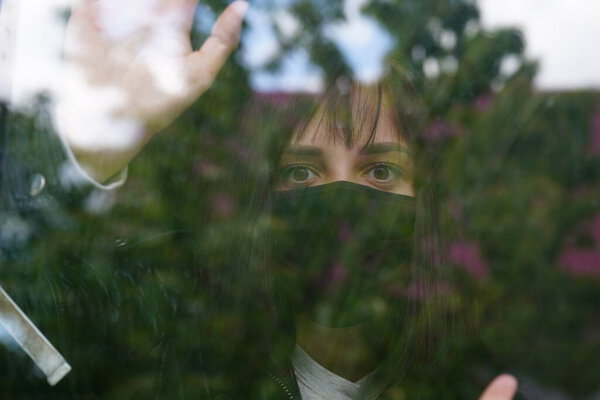 Thoughtful female with brown eyes observing through window.