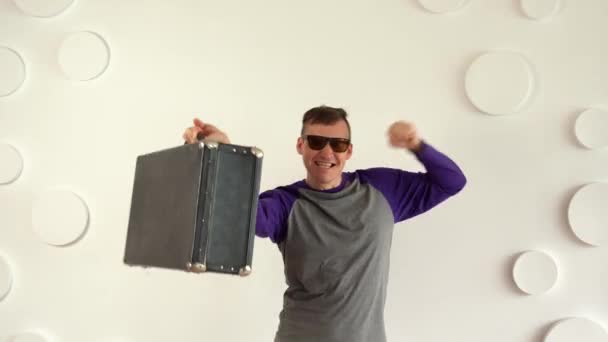 Junger Mann Mit Sonnenbrille Und Großem Koffer Vor Weiß Gemusterter — Stockvideo