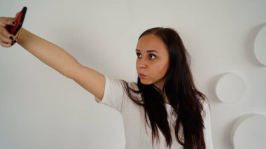 Hafta sonunu evde geçiren bir kadının portresi ve cep telefonuyla kendi fotoğrafını çekmesi..