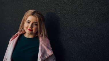 Gri bir duvarın arkasında poz veren güzel bir kızın portresi.