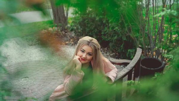 緑の植生の近くのベンチに座っている美しい少女の肖像画 — ストック写真