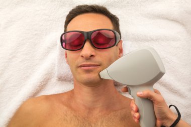 Man with glasses in spa salon laying on white towel clipart