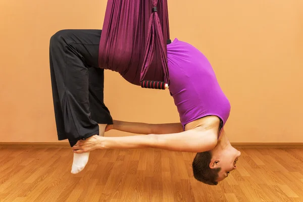 Pregnant woman making aerial yoga exercises, indoor