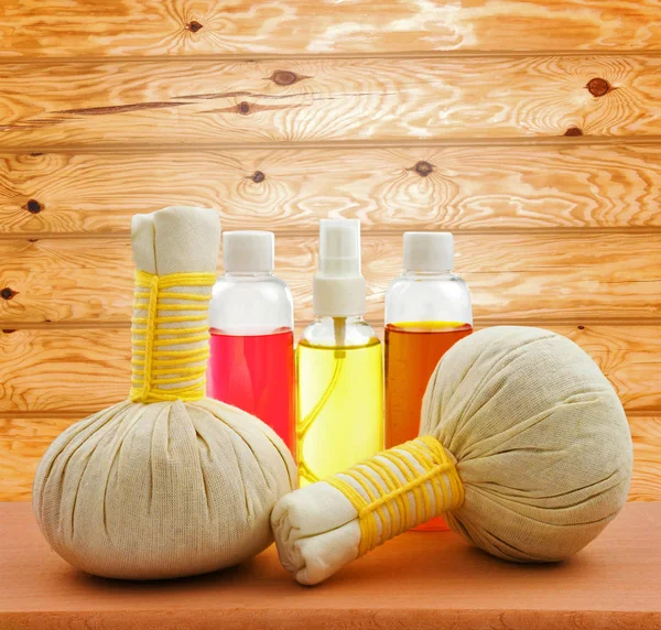 Concept of spa compress balls with bottles of aroma oil on woode — Stock Photo, Image