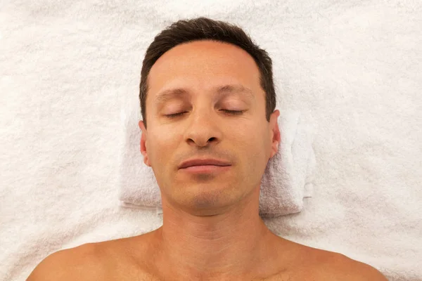Adam beyaz havlu üzerinde döşeme spa salonda rahatlatıcı — Stok fotoğraf