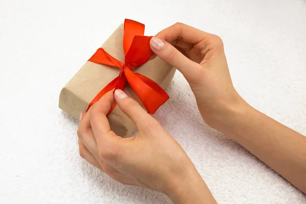 Beautiful caucasian female hands with present with red ribbon — Stock Photo, Image