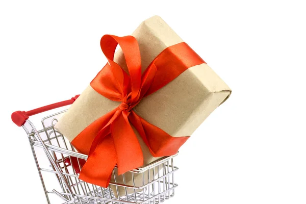 Gift with wrapping paper and red ribbon bow in the shopping cart — Stock Photo, Image