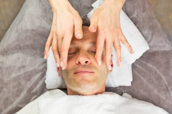 Mužská tvář s Krémová maska, ruce profesionální kosmetičky — Stock fotografie