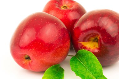 Beyaz arkaplanda yeşil yapraklı kırmızı elmanın makro görünümü