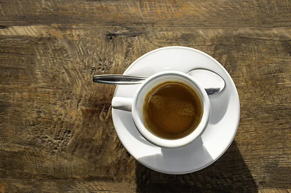Горячий кофе в белой чашке с блюдцем на деревянном столе — стоковое фото