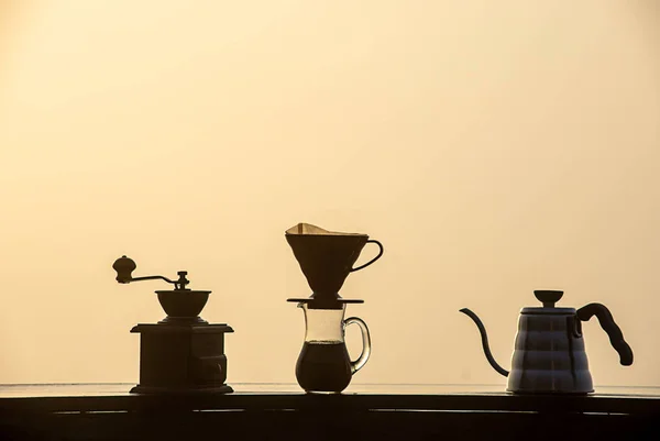 Drewniana szlifierka do kawy, szklane słoiki i czajniki na drewnianym stole. — Zdjęcie stockowe