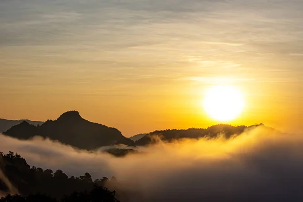 Salida del sol y luz de la mañana detrás de las montañas con la niebla cubierta . — Foto de Stock