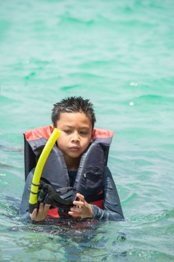 Can yeleği giymiş Asyalı Çocuk portresi ve denizde dalış maskesi..