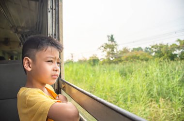 Trendeki Asyalı çocuğun portresi. Pencere ve ağaçlar..
