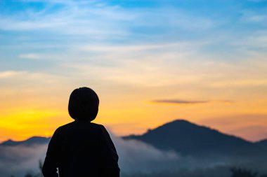 Bulanık sabah güneşi dağların ardında bir kadının gölgesi ve sisin içinde..
