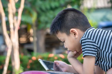 Asyalı çocukların portresi parkta cep telefonu çalıyor.