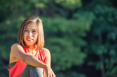 Arkaplanda oturan Asyalı kadın portresi bulanık ağaçlar