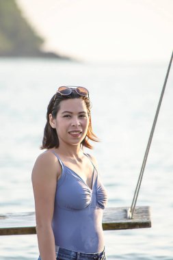 Mayo giymiş Asyalı bir kadının portresi. Deniz ve gökyüzü.