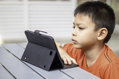 Parkta cep telefonu çalan Asyalı çocuğun portresi.