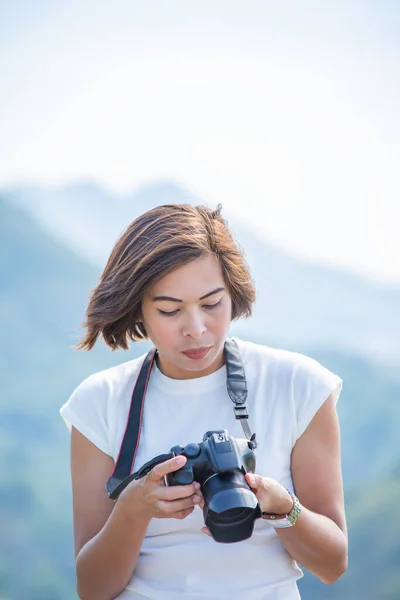 Hand woman holding the camera background Kaeng Krachan dam phetchaburi , Thailand.