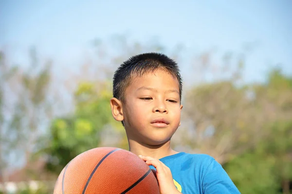 Azji Chłopiec Gospodarstwa Koszykówka Piłka Tło Niewyraźne Drzewa — Zdjęcie stockowe
