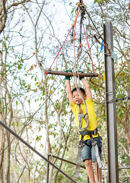 Asean boy hanging rod Tied with ropes and slings background blurry tree.