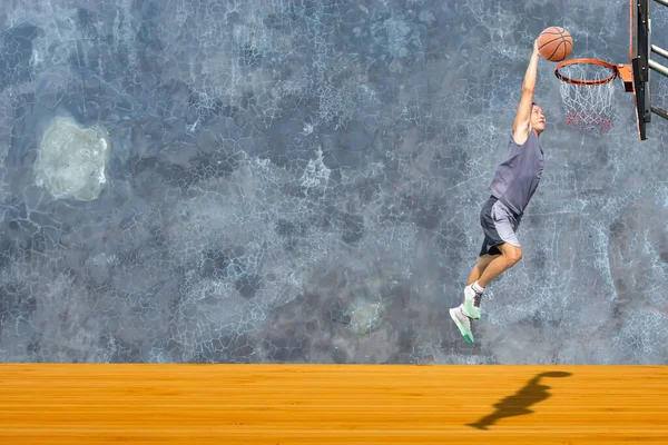 Basketball in hand man jumping Throw a basketball hoop On the wooden floor Background plaster wall loft  with The pattern of cracks.