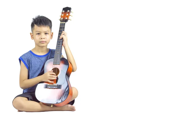 亚洲男孩手里拿着一把吉他 坐在白色的背景上 走着快捷方式 — 图库照片