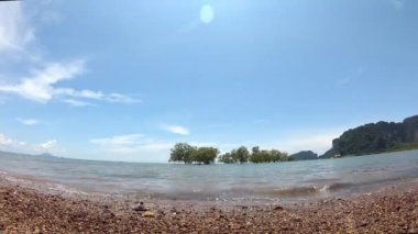 Hızla hareket eden okyanus dalgaları denizdeki arka plana vurur ve bulutlar gökyüzünde hızla hareket eder..