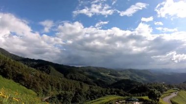 Video, sarı çiçek tarlalarının solundan sağa veya Tithonia diversifolia 'dan (Hemsl) hareket eder. A.Gray. Dağlarda arka planda gökyüzünde güzel bulutlar ve Doi Mae Ukho 'da yol, Mae