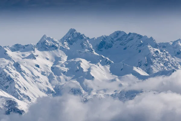 Піки снігових гір, покриті хмарами на сонці — стокове фото