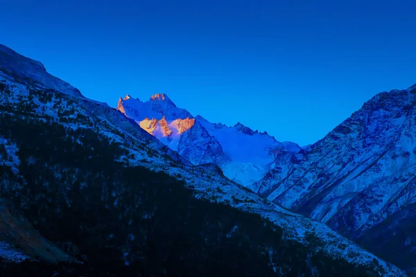 Pôr-do-sol brilhante sobre picos de montanha caucasianos azuis no anoitecer da manhã de inverno — Fotografia de Stock