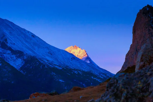 Mavi beyaz dağ zirveleri üzerinden parlak günbatımı kış sabah alacakaranlıkta — Stok fotoğraf