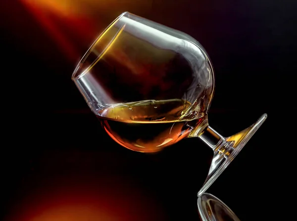 Cognac in vetro da vino inclinato con illuminazione ambrata — Foto Stock