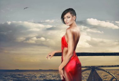 Kırmızı elbiseyi deniz iskelesi akşam poz güzel zarif genç esmer portresi 