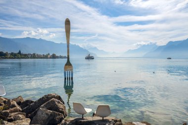 VEVEY, SWITZERLAND - SEPTEMBER 29, 2017: Landscape with fork sculpture in Geneva lake. Artist  Jean-Pierre Zaugg    clipart