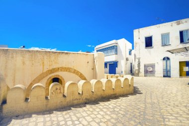 Street scene with part of fortress wall and white houses in Sousse. Tunisia, North Africa       clipart