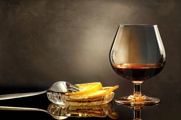 コニャック ワイングラスやガラスのテーブルの上のフォークとレモンのスライス — ストック写真