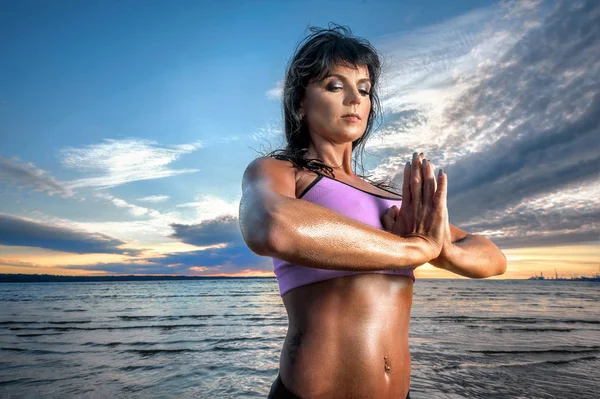 有吸引力的健身妇女的画像在瑜伽位置放松在海景背景日落 — 图库照片